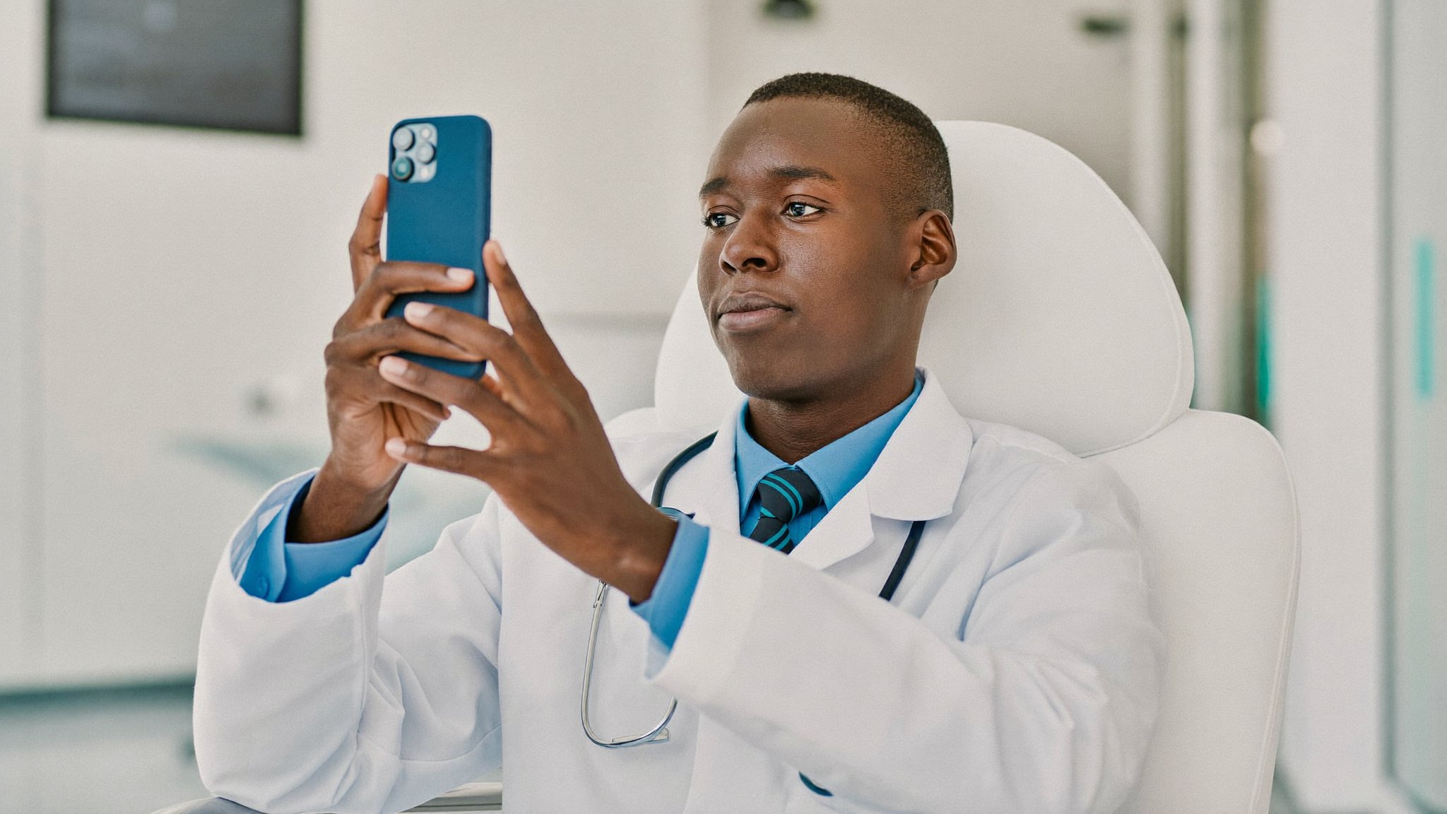 Médico usando o celular em uma clínica moderna e clara, produzindo conteúdo para redes sociais